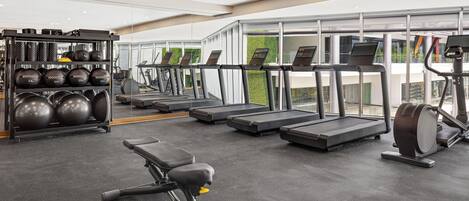 A modern gym with treadmills, a rowing machine, and a bench press.