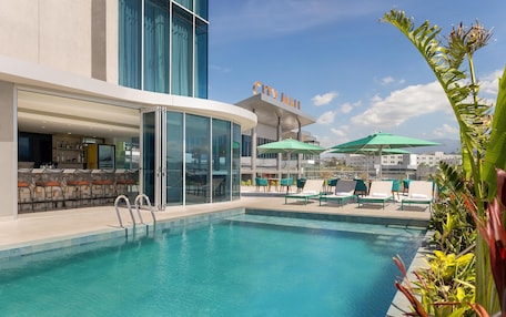 A pool area with lounge chairs and umbrellas, a bar, and a 'City Mall' sign.