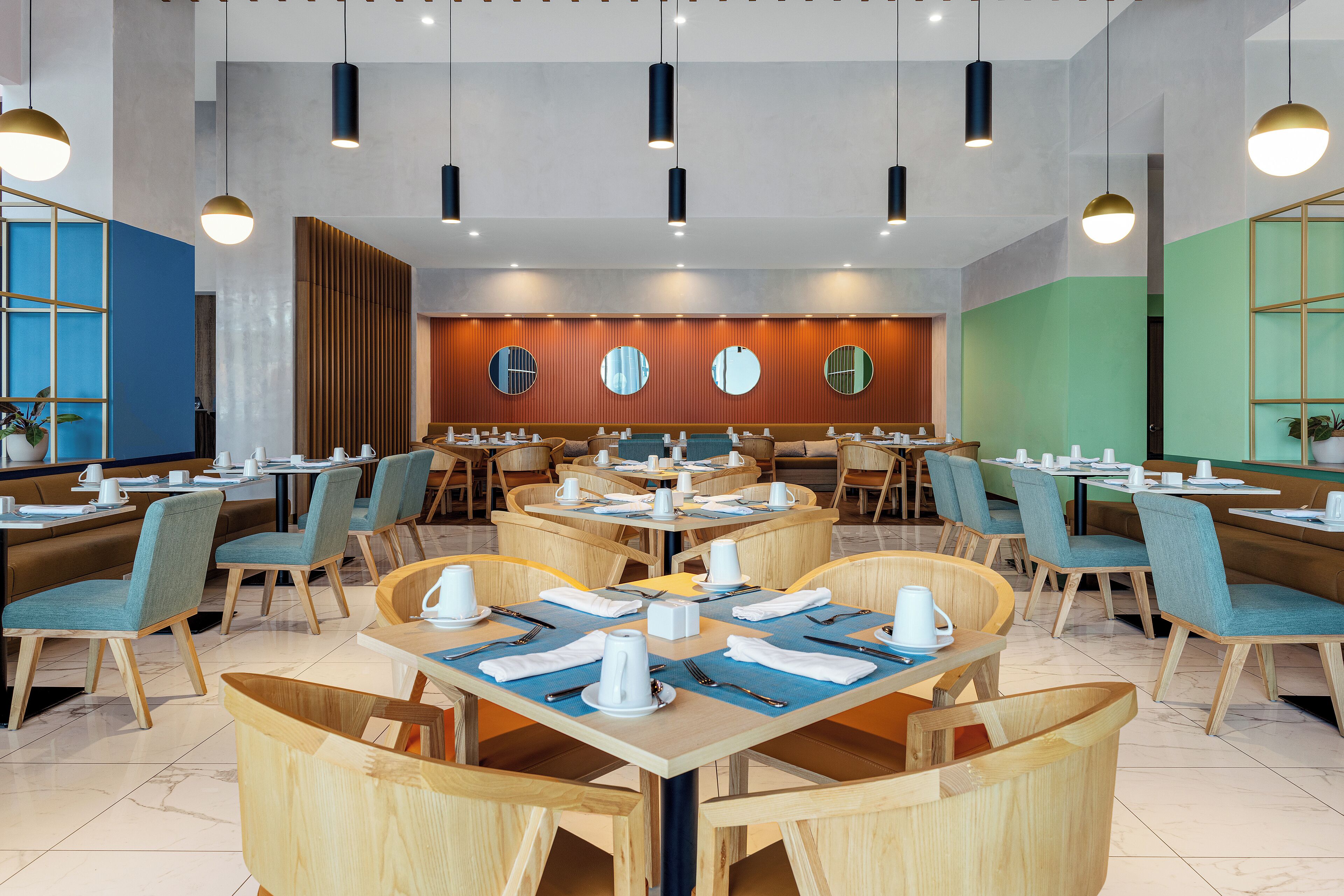 A modern dining area with round tables, blue chairs, and wooden accents.