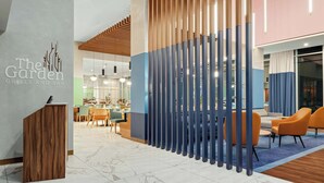 A modern interior with a reception desk, seating area, and a partition with vertical slats. - Hilton Garden Inn San Jose Airport City Mall (Alajuela)