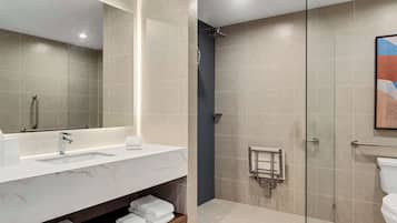 A modern bathroom with a large mirror, a sink, and a shower area.