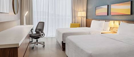 Ein Hotelzimmer mit zwei Betten, einem Schreibtisch, einem Stuhl und einem großen Fenster mit Vorhängen.