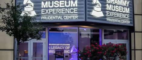 The Grammy Museum Experience at the Prudential Center with a neon sign and a planter with flowers.