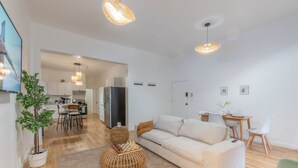 A modern living room with a sofa, a coffee table, and a dining area with chairs and a table.