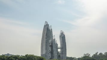 Un edificio moderno de gran altura con un diseño arquitectónico único, rodeado de vegetación.