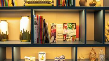 Una estantería con libros, objetos decorativos y una máquina de escribir.