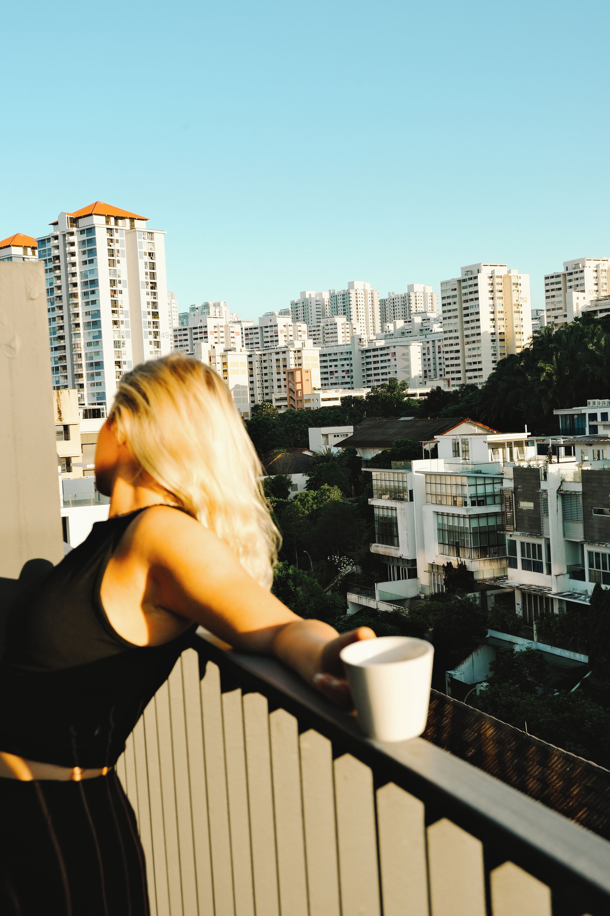 Una persona en un balcón con vistas a un paisaje urbano de edificios modernos.