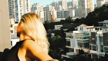 Una persona en un balcón con vistas a un paisaje urbano de edificios modernos.