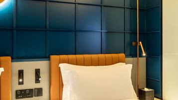 Een hotelkamer met een groot bed, een nachtkastje met een telefoon en een wandlamp.