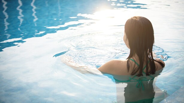 Una persona en una piscina con agua cristalina y reflejos de luz en la superficie.