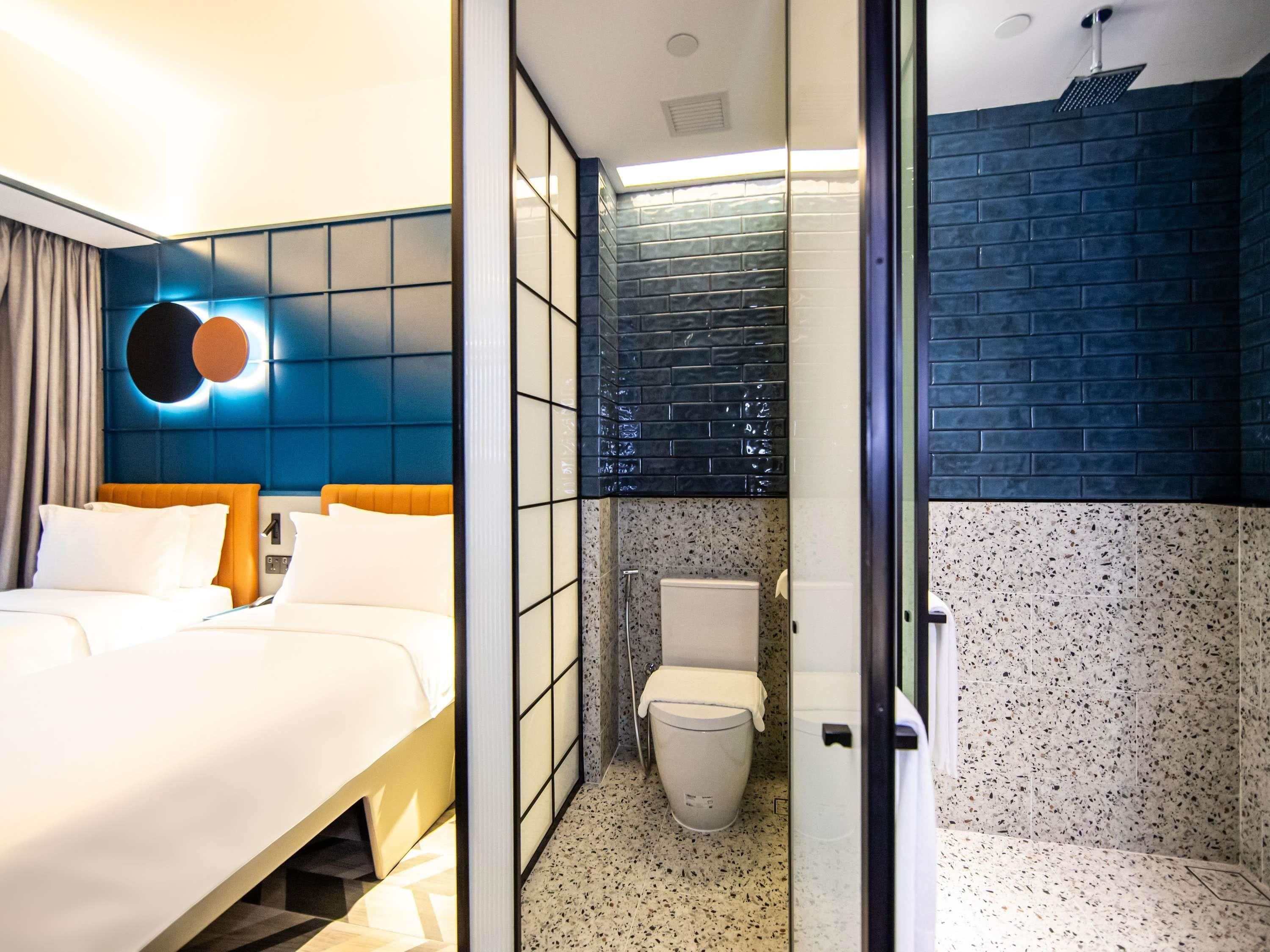 A hotel room with a bed, a bathroom with a shower, and a toilet.