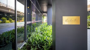 Een moderne hotelgang met glazen wanden, kamerplanten en een bordje met de tekst 