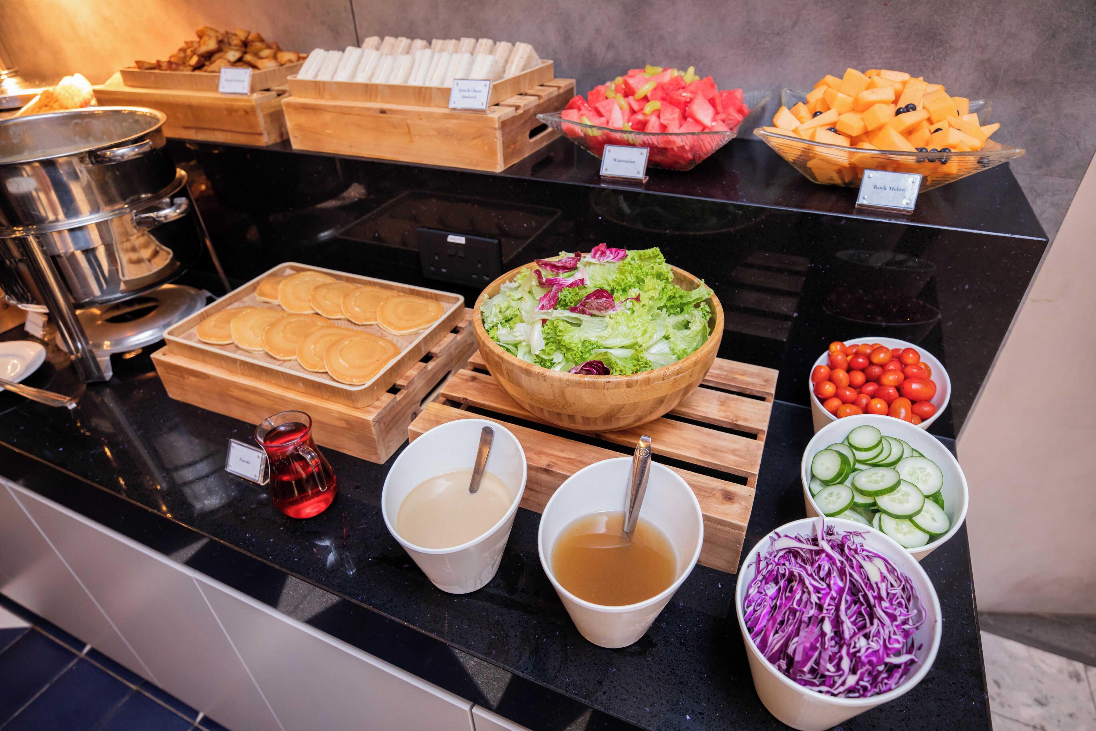 A buffet with various food items including pancakes, salads, and fruits.