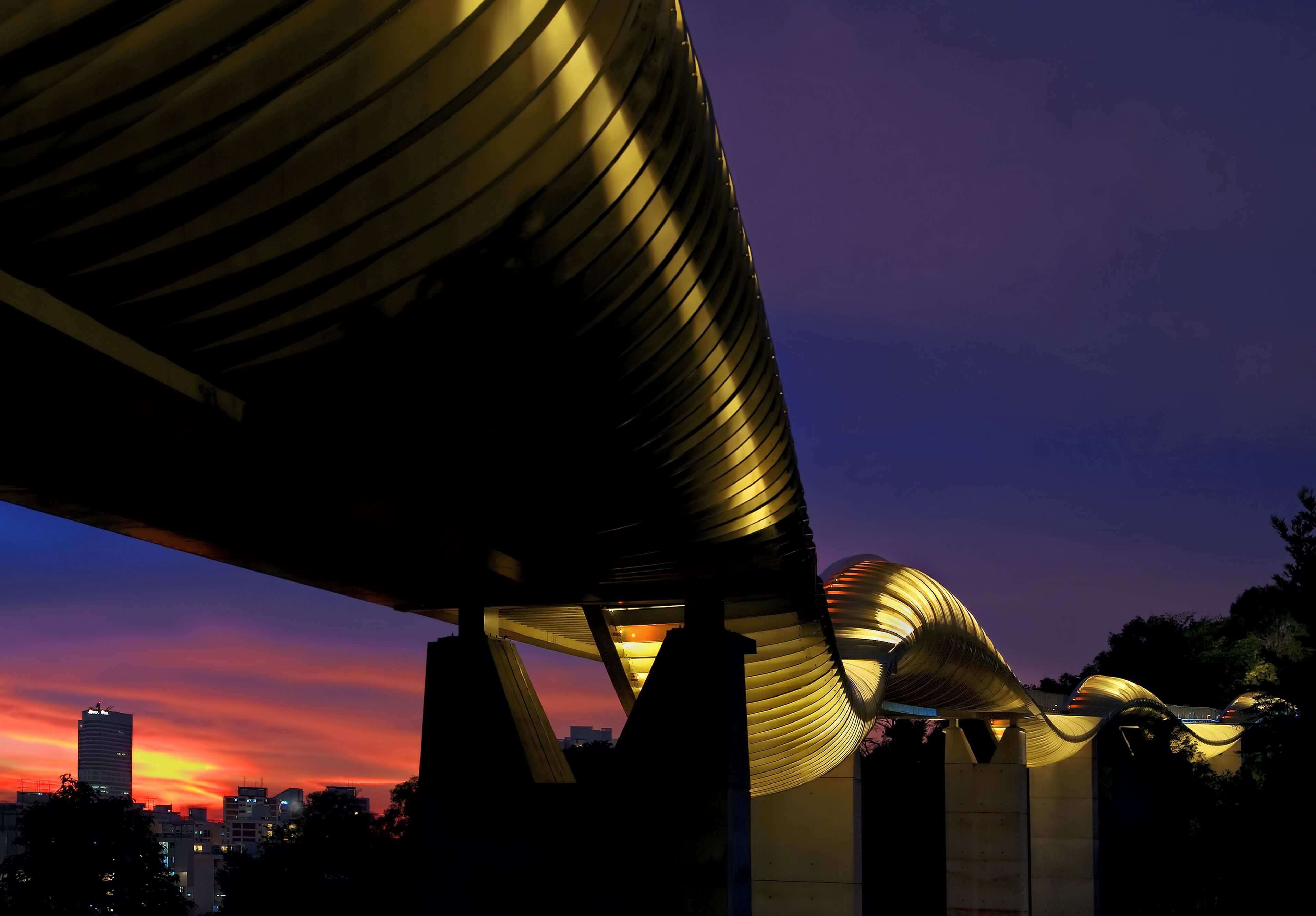 A modern architectural structure with a curved roof design, likely a public building or landmark, set against a twilight sky.