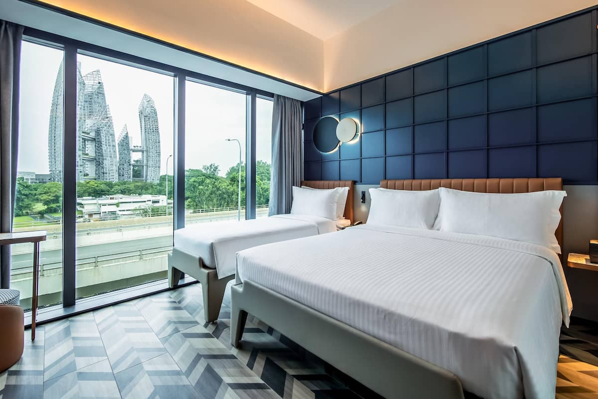 Habitación de hotel con dos camas, ventanas amplias, vistas a edificios de la ciudad y un diseño moderno.