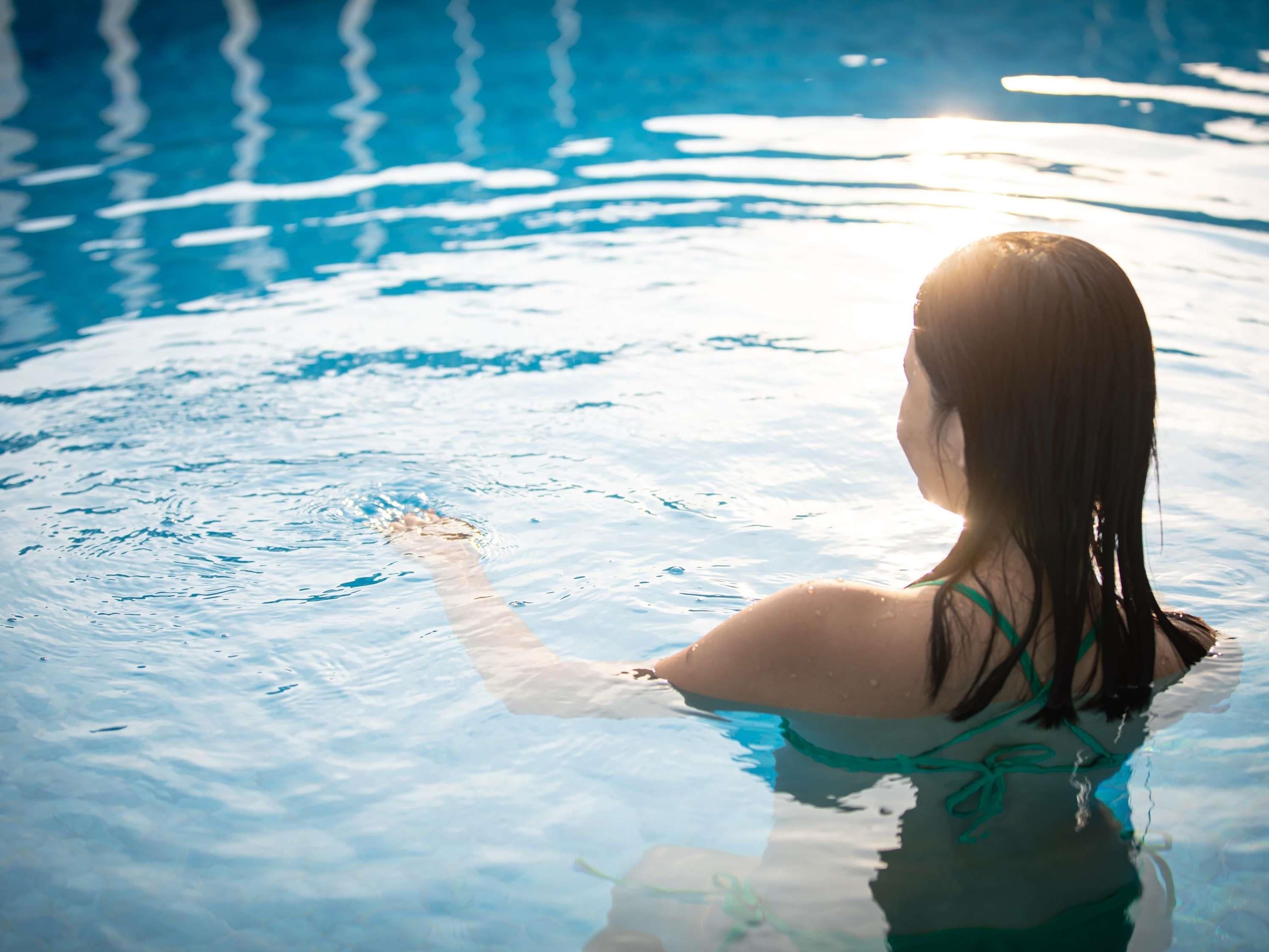 Una persona en una piscina con agua cristalina y reflejos de luz en la superficie.