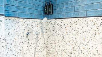 A bathroom with blue tiled walls and a speckled tile floor.