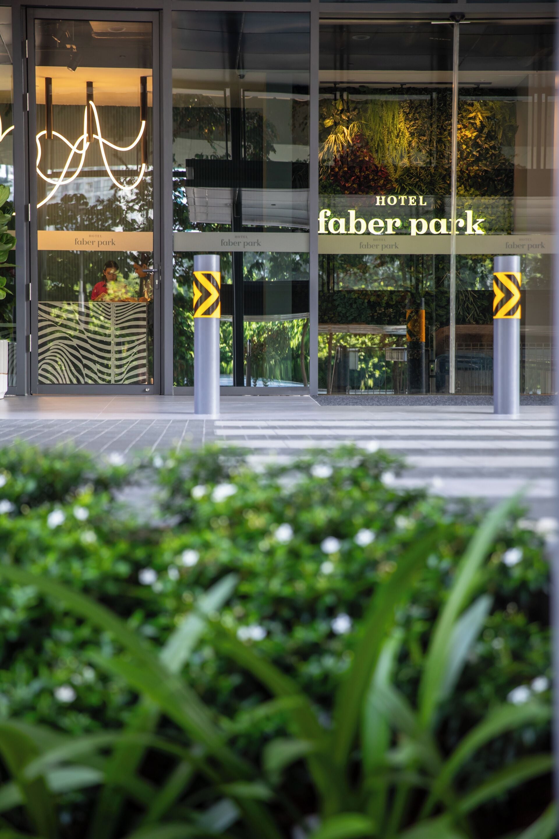 La entrada del Hotel Faber Park con puertas de cristal, un diseño a rayas de cebra y un cartel con el nombre del hotel.