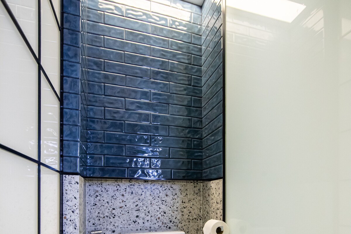 A bathroom with a toilet, shower, and a towel rack.