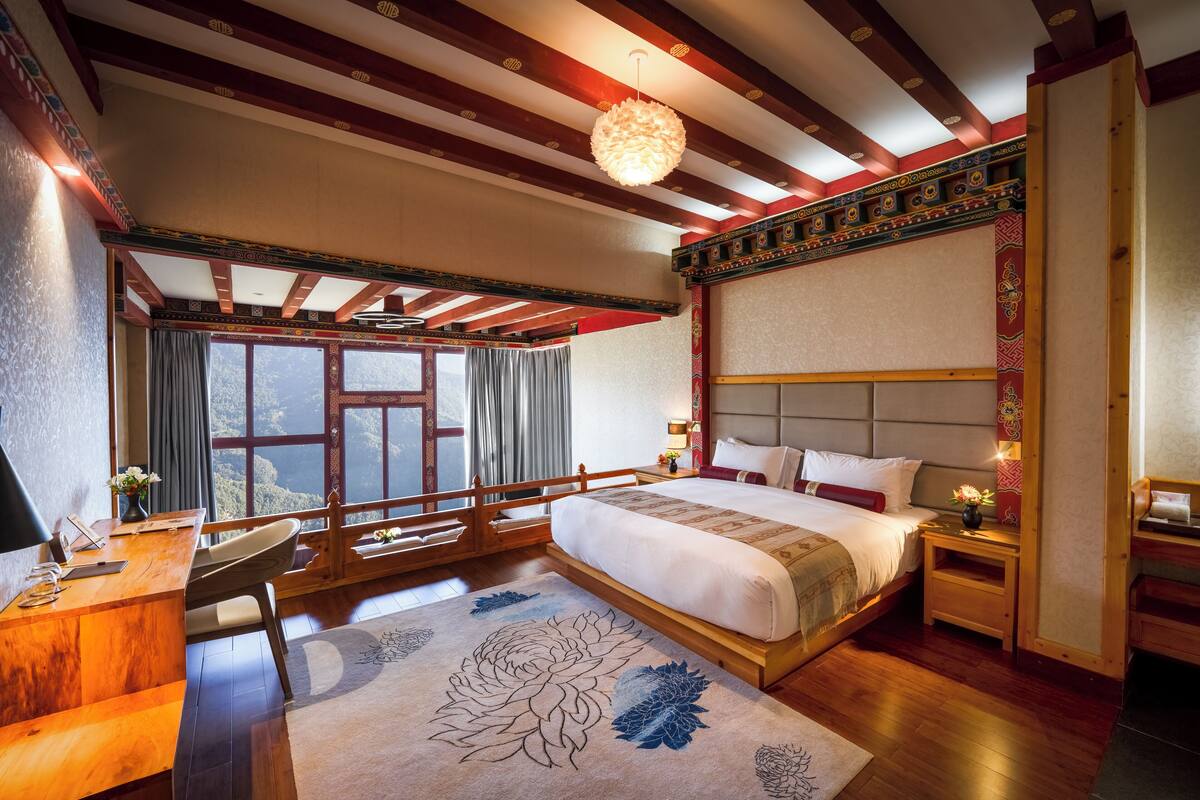 A spacious bedroom with a large bed, wooden furniture, and a view of the mountains.