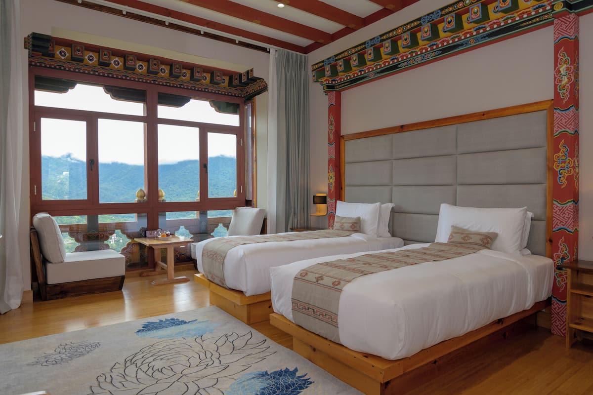 A room with two beds, a sofa, and a view of mountains.