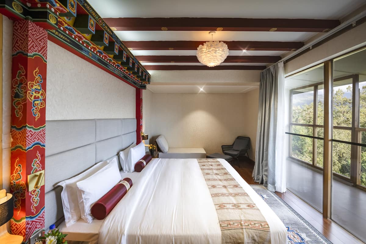 A hotel room with a large bed, a desk, a chair, and a view of the outdoors.