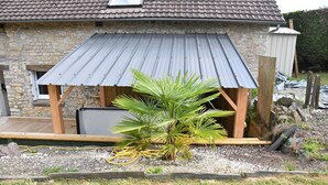 Ein rustikales Steinhaus mit Metalldach und Holzterrasse.