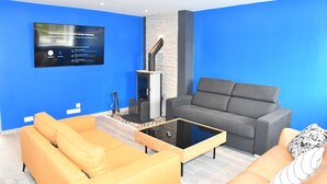 Ein modernes Wohnzimmer mit einem an der Wand befestigten Flachbildfernseher, einem Kamin und einem grauen Sofa.