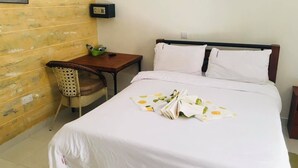 Habitación de hotel con cama, un escritorio pequeño, una silla y un dispositivo de seguridad fijado a la pared.