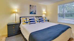 Quarto com cama, duas mesas de cabeceira, janela com persianas e um quadro pendurado na parede.