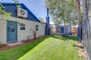 A residential backyard with a well-maintained lawn, a blue door, a brick chimney, and a patio area with outdoor furniture. - MidTown Reno Vacation Rental w/ Fenced-In Yard! (Reno)