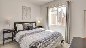 A bedroom with a bed, nightstands, a window with curtains, and a wall-mounted artwork. - MidTown Reno Vacation Rental w/ Fenced-In Yard! (Reno)