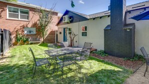 A backyard with a metal table and chairs, a brick house, and a blue awning. - MidTown Reno Vacation Rental w/ Fenced-In Yard! (Reno)