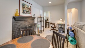 A cozy living room with a fireplace, a dining table with placemats, a sofa, and a yoga mat. - MidTown Reno Vacation Rental w/ Fenced-In Yard! (Reno)