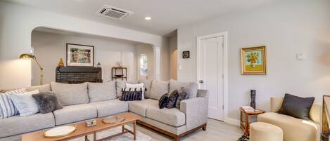 A living room with a sectional sofa, a small ottoman, a coffee table, and a side table with a lamp.