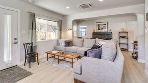 A living room with a sofa, a coffee table, a chair, and a fireplace. - MidTown Reno Vacation Rental w/ Fenced-In Yard! (Reno)
