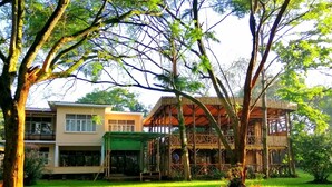 Un edificio de dos pisos con techo verde y estructura de madera con tejado de paja.