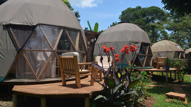Varias tiendas en forma de cúpula con muebles de madera y un jardín.