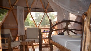Alojamiento tipo tienda confortable con cama, zona de estar y vistas al exterior.