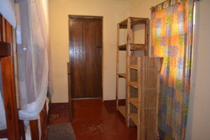 Un pasillo estrecho con una puerta de madera, un estante de madera y una cortina colorida.