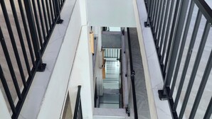 A multi-level interior with a central staircase surrounded by black railings and white walls. - Eliper Hotel (Gatura)