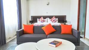 A modern hotel room with a grey sofa, two round white tables, and a book on one table. - Eliper Hotel (Gatura)