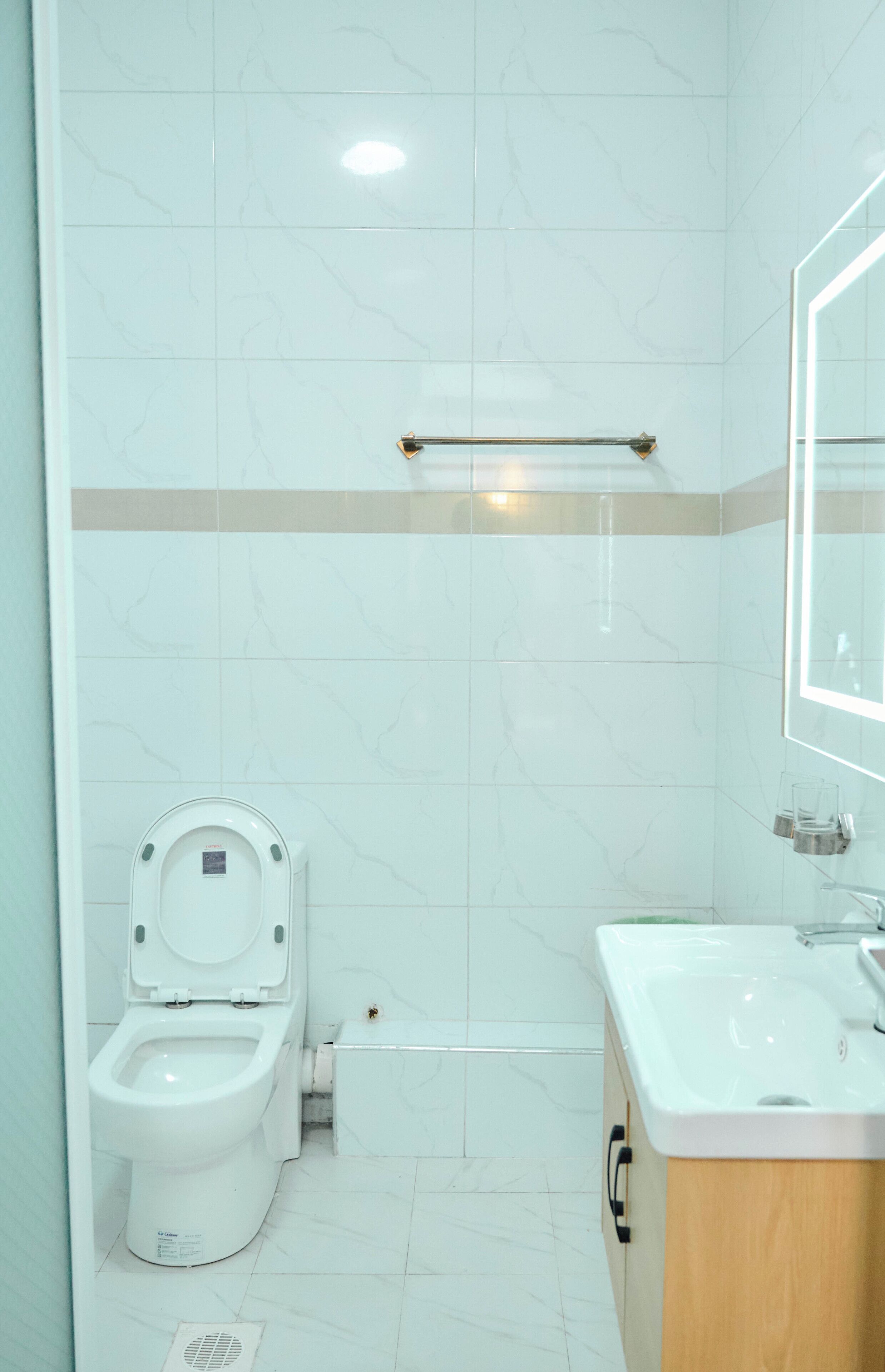 A bathroom with a toilet, sink, and mirror.