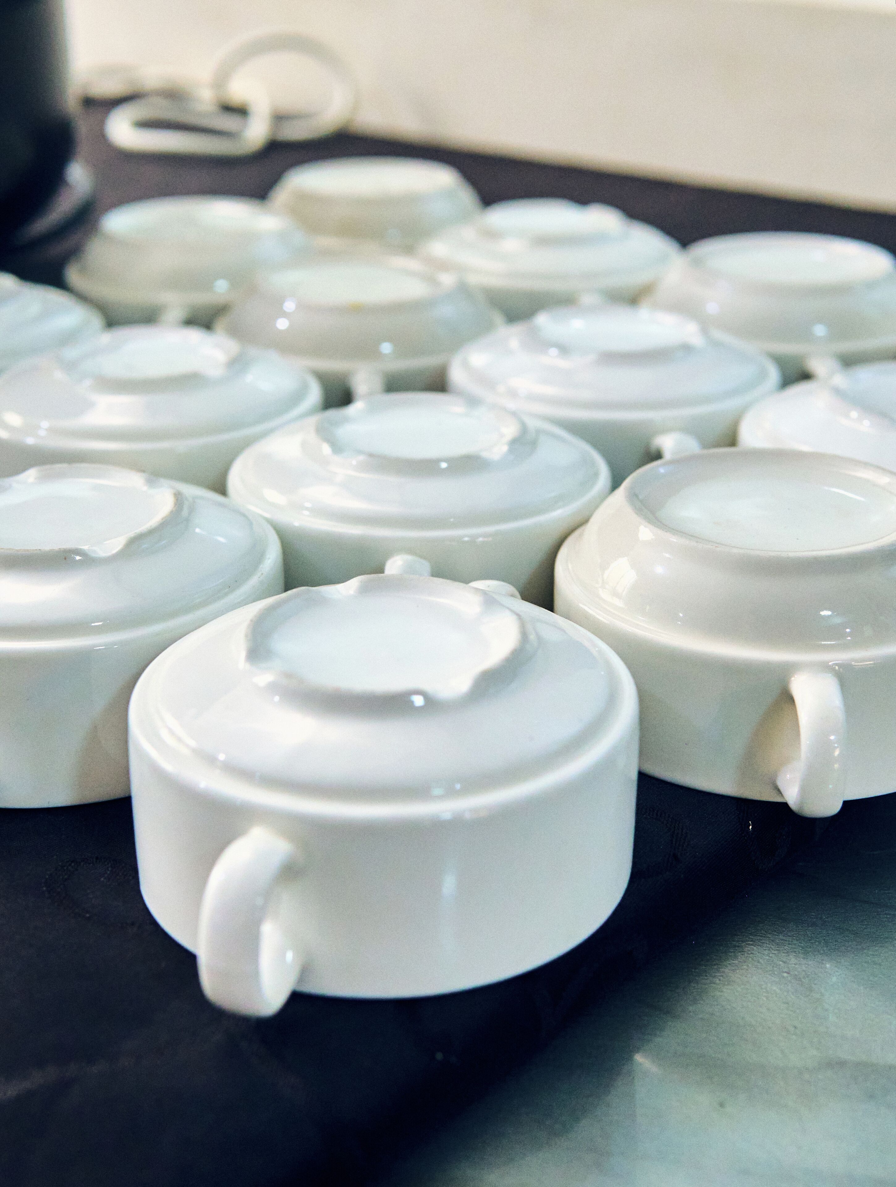 A collection of white ceramic teapots with lids, arranged on a black surface.