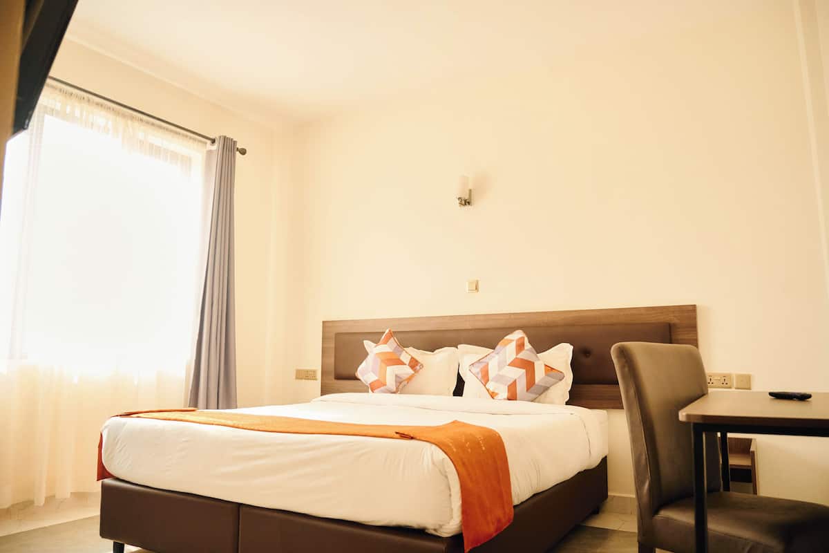 A hotel room with a bed, a desk, and a chair.