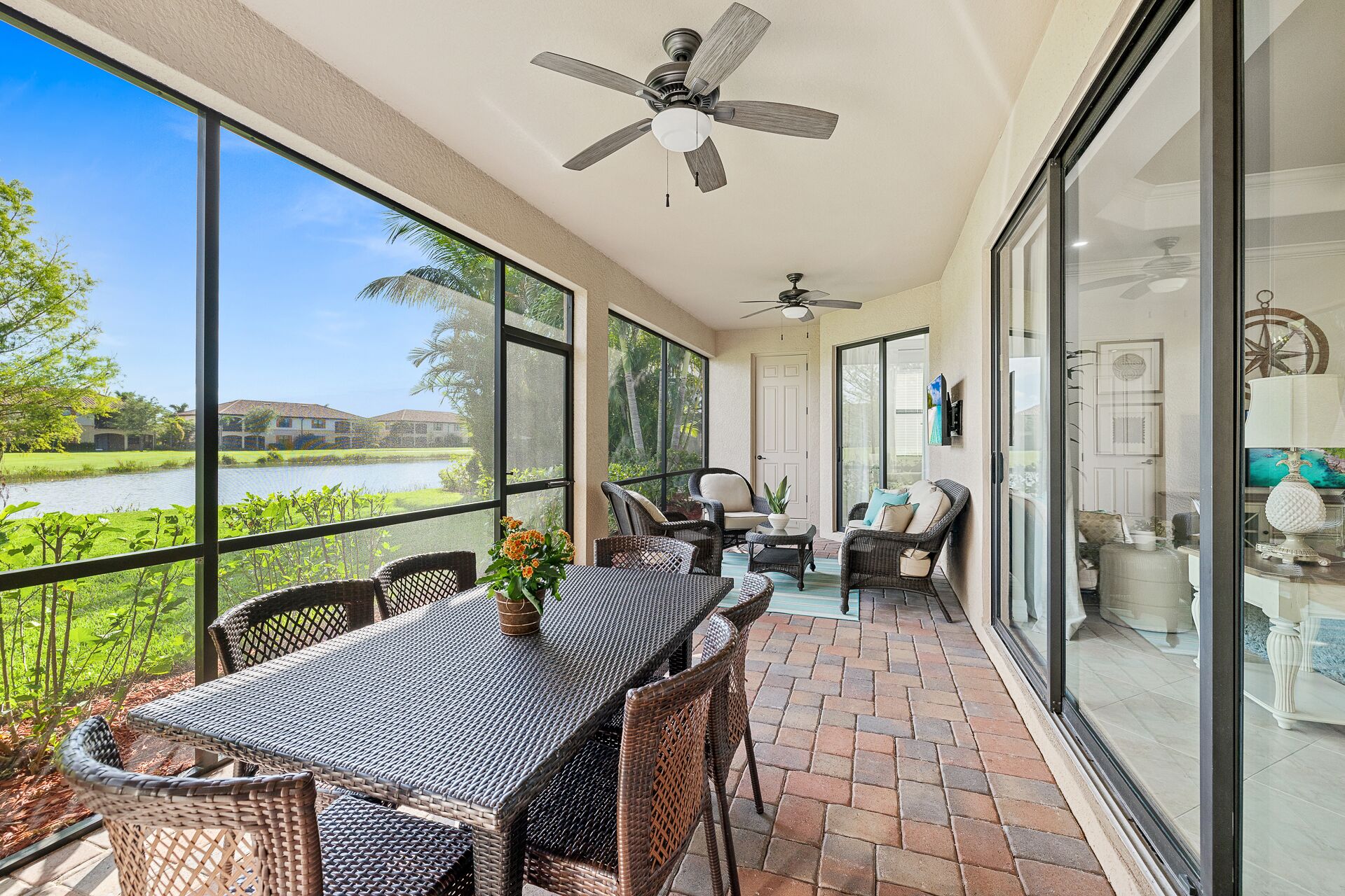 A spacious balcony with a table and chairs, overlooking a body of water and greenery.