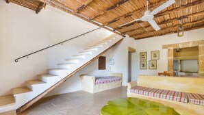 Un escalier menant à une chambre située en mezzanine, aménagée avec un lit, un canapé et une grande plante verte.