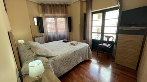 Un dormitorio con cama, lámpara de noche, cómoda y vistas al exterior.