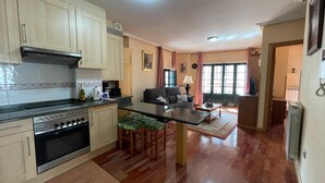 Una cocina amplia con una isla central, suelo de madera y un rincón comedor con sofá y mesa.