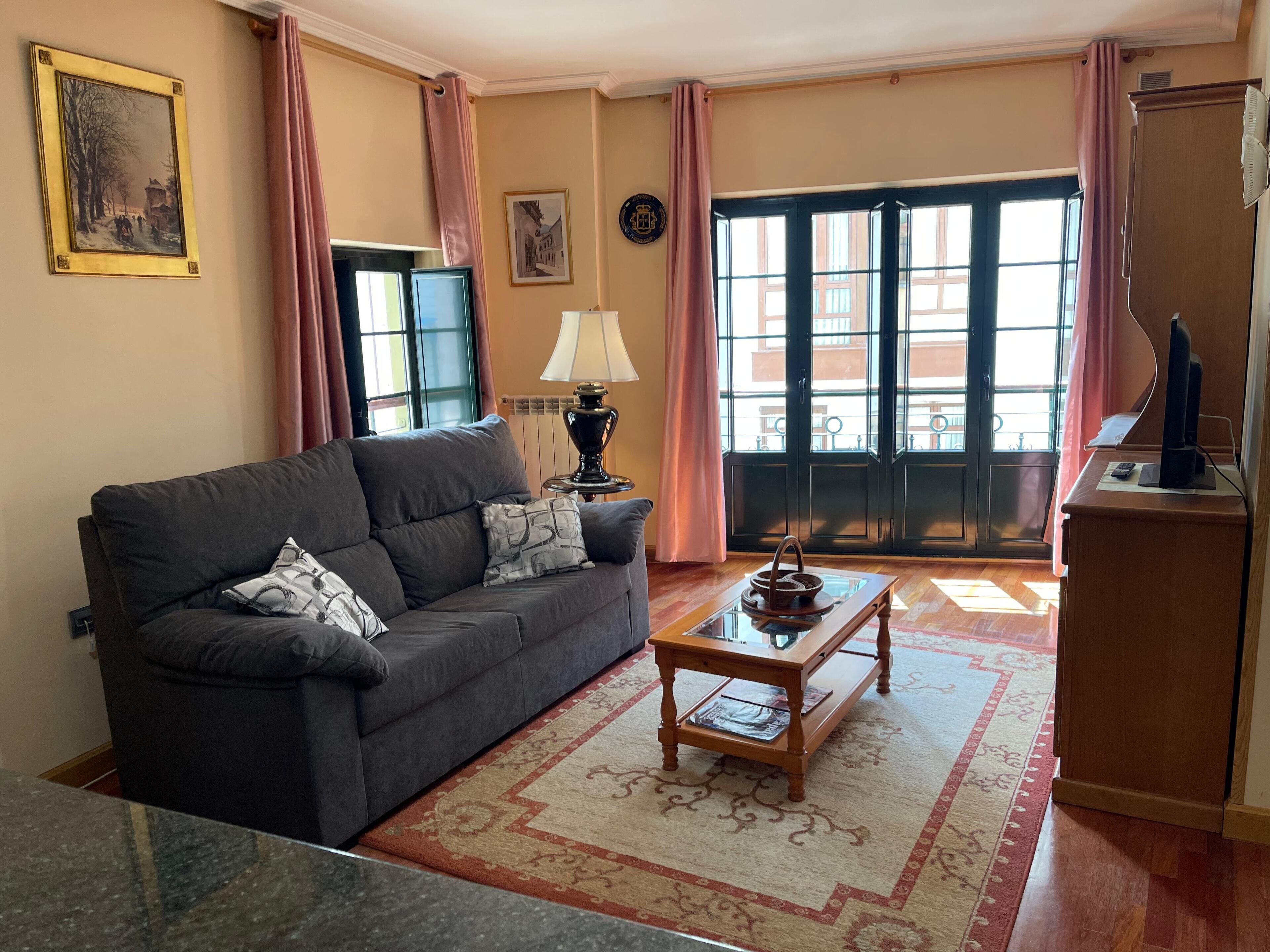 A living room with a sofa, a coffee table, a lamp, and a television.